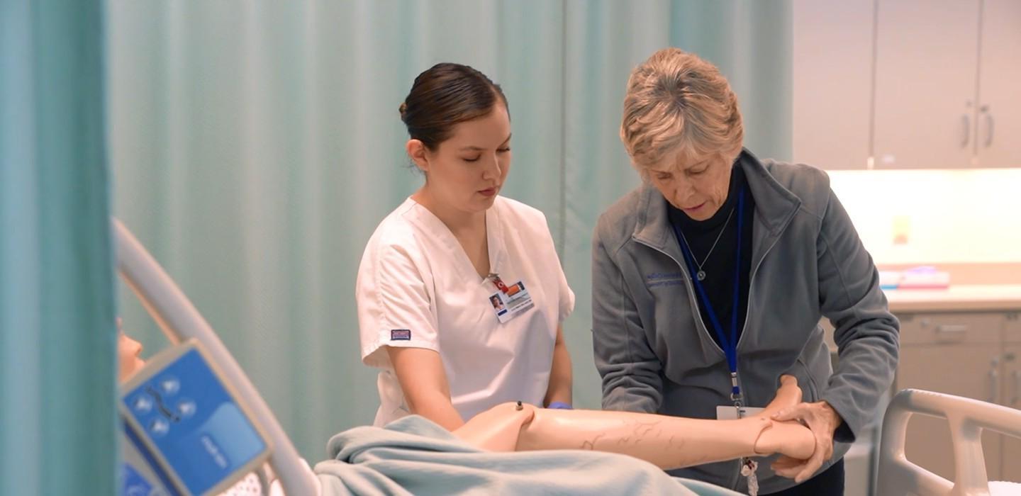 澳门皇家赌城在线CNA教员向CNA学生演示病人护理